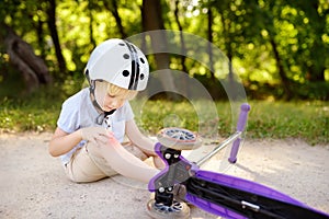 Toddler boy in safety helmet learning to ride scooter