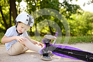 Toddler boy in safety helmet learning to ride scooter