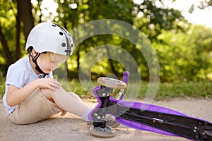 Toddler boy in safety helmet learning to ride scooter