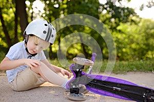 Toddler boy in safety helmet learning to ride scooter