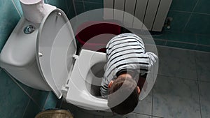 Toddler boy shows how he washes the toilet with a cleaning sponge. Fun child's play at home. Little helper concept.