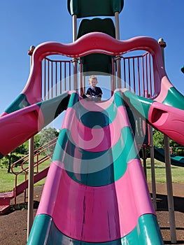 Toddler Boy Sitting Atop a Tall Slippery Slide