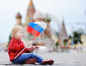 Toddler boy sitting and playing with russian flag