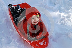 Toddler boy sledding in the snow