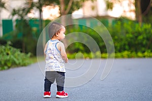 Toddler boy is standing in the park, a 1 year old child is learning to walk. Empty space for entering text