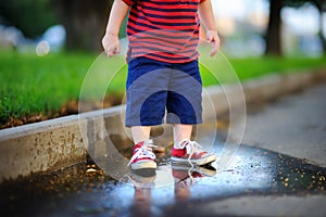 Toddler boy standing in a puddle