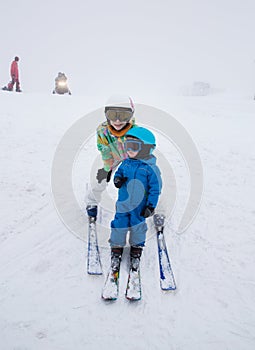 Toddler boy and teenage girl skiing in the mountains