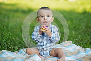 Toddler boy is teething. Baby gnaws toy while walking in park. Concept of childhood and nursery