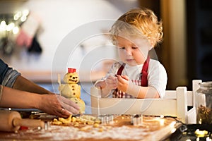 Toddler boy making gingerbread cookies at home.