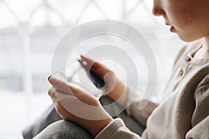 Toddler boy using tablet or smartphone. Cute five years old boy sitting at home using digital device.