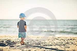 Toddler boy walking on a sunny beach