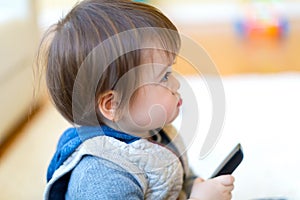 Toddler boy watching TV with a remote control