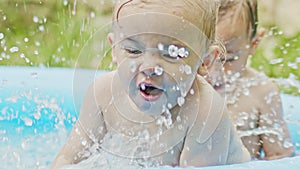 Toddler boys twins swimming together in blue outdoor pool. Brothers smiling, having fun, enjoy splashing water. Concept