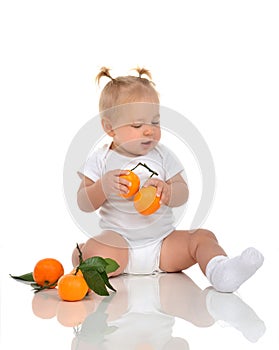 Toddler child baby girl happy sitting smiling screaming with fresh orange mandarin