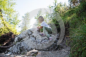 Toddler child climbing the rock on a hiking trail