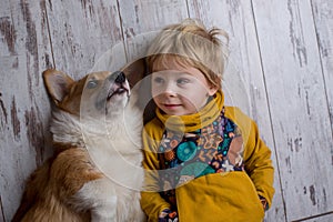 Toddler child and dog, boy and puppy playing together at home