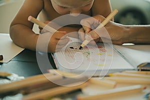 Toddler child drawing with color pencils with her mother