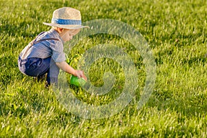 Toddler child outdoors. One year old baby boy wearing straw hat using watering can