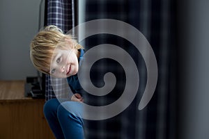 Toddler child, sitting on the window, watching the snow falling, reading a book