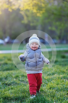 Toddler child in warm vest jacket outdoors. Baby boy at park.