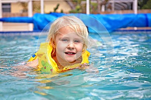 Toddler Child Wearing Inflatable Life Jacket Learning to Swim in Backyard Family Pool