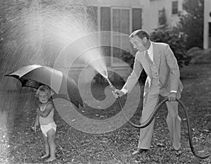 Toddler and dad playing with hose in yard