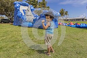 A toddler does his happy dance while watching a bounce house inflate