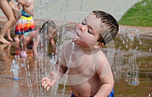 Toddler drinking in a summer fountain photo