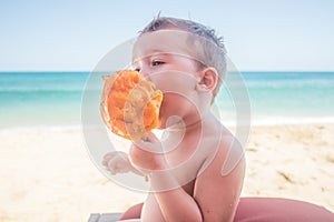 Toddler Eating a Freshly Sliced Mango on the Beach