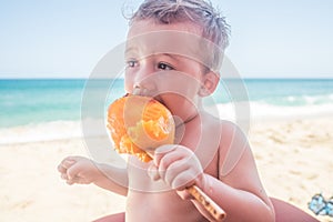 Toddler Eating a Freshly Sliced Mango on the Beach