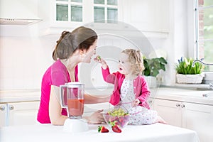 Toddler girl and adorable mother making fresh strawberry