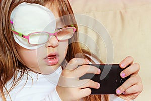 Toddler girl with bandage on eye playing games
