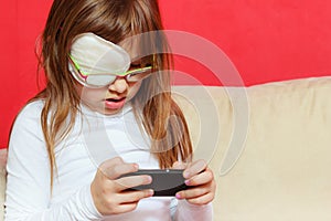 Toddler girl with bandage on eye playing games