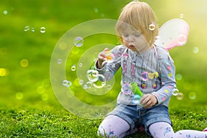 Toddler girl with butterfly wings having fun in park