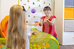 Toddler girl in child occupational therapy session doing playful exercises with her therapist.