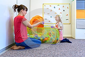 Toddler girl in child occupational therapy session doing playful exercises with her therapist. photo