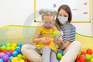 Toddler girl in child occupational therapy session doing playful exercises with her therapist during Covid - 19 pandemic.