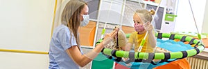 Toddler girl in child occupational therapy session doing playful exercises with her therapist during Covid - 19 pandemic.