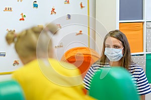 Toddler girl in child occupational therapy session doing playful exercises with her therapist during Covid-19 pandemic.