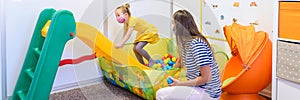 Toddler girl in child occupational therapy session doing playful exercises with her therapist during Covid-19 pandemic.