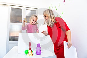 Toddler girl in child occupational therapy session doing sensory playful exercises with her therapist.