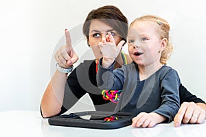 Toddler girl in child occupational therapy session doing sensory playful exercises with her therapist.