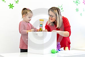 Toddler girl in child occupational therapy session doing sensory playful exercises with her therapist.