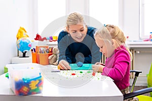 Toddler girl in child occupational therapy session doing sensory playful exercises with her therapist.