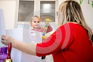 Toddler girl in child occupational therapy session doing sensory playful exercises with her therapist.