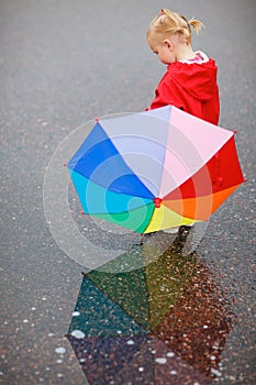 Toddler girl with colorful umbrella on rainy day