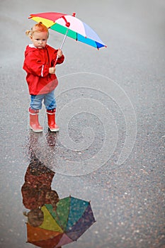 Toddler girl with colorful umbrella on rainy day