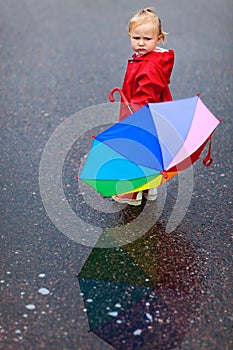 Toddler girl with colorful umbrella on rainy day