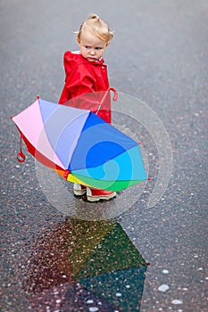 Toddler girl with colorful umbrella on rainy day