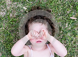 Toddler girl covering eyes from above